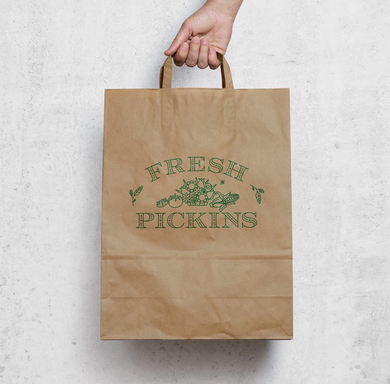 The Fresh Pickins logo is outlined in green on a brown craft grocery bag.