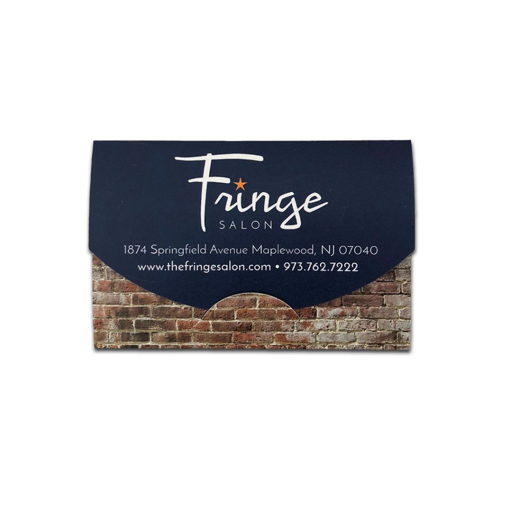 Fringe Salon gift card enclosure | Closed gift card enclosure looks like envelope with rounded flap. Flap is navy with white logo, connecting to brick pattern.