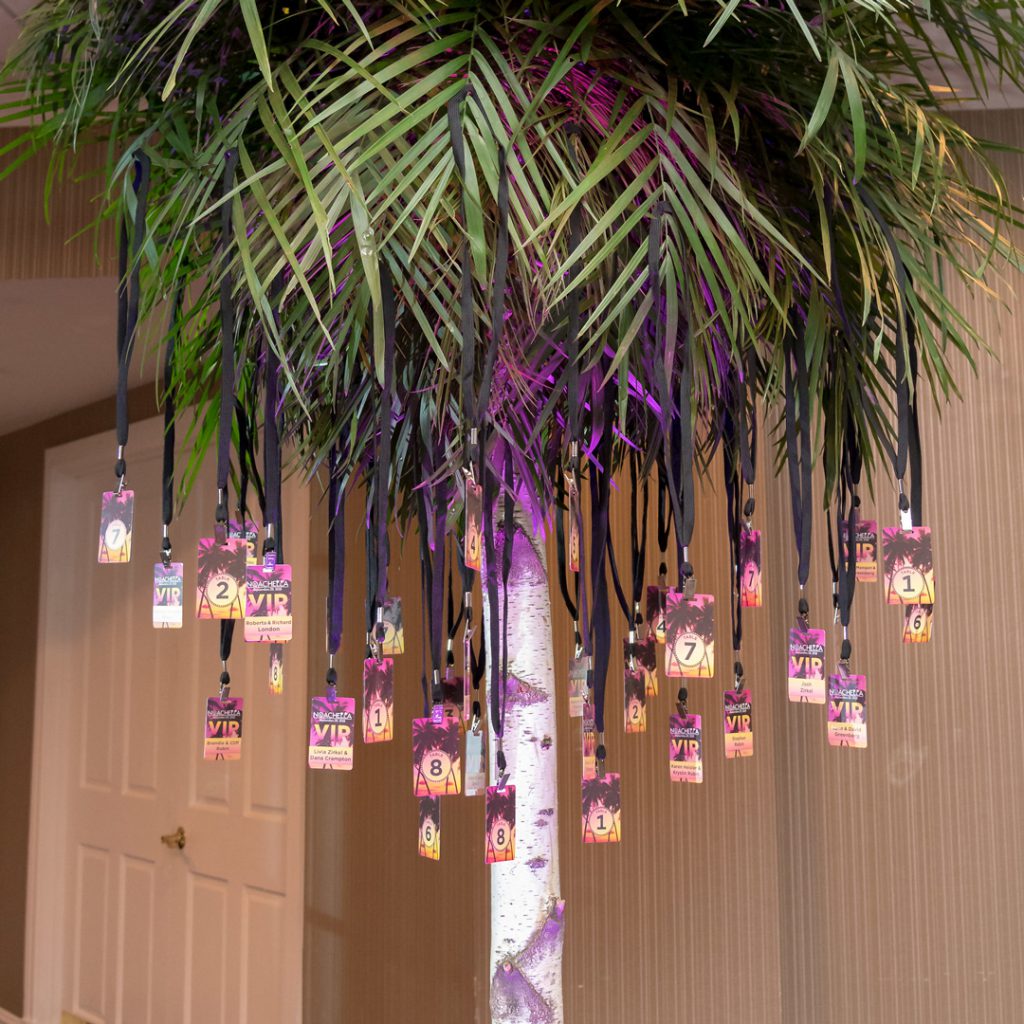 Life-size palm tree with VIP table numbers hung from branches.